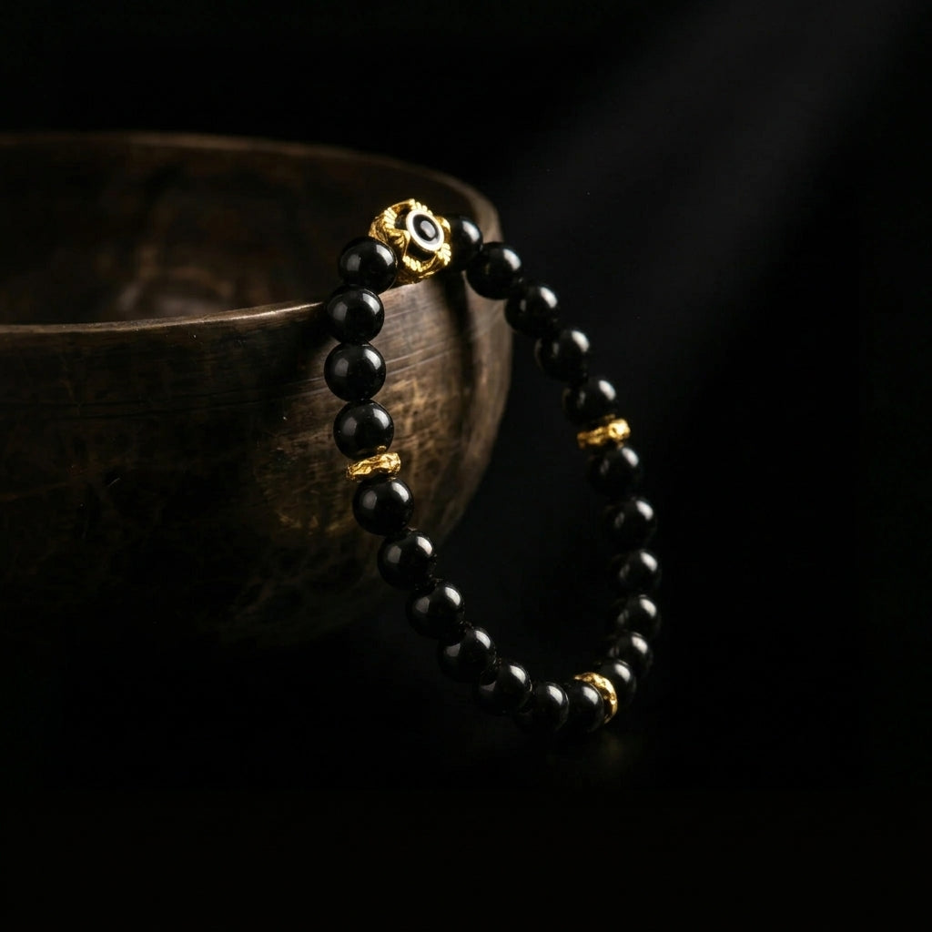 Jambhala Black Obsidian mindfulness bracelet resting on an ancient singing bowl, prepared for the 1,900-meter sound purification ritual to clear heavy energy.