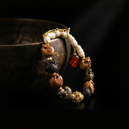 Diverse hand-carved Memento Mori skull bracelet draped over a dark rustic bowl, highlighting the varied organic materials and the dangling red agate charm.