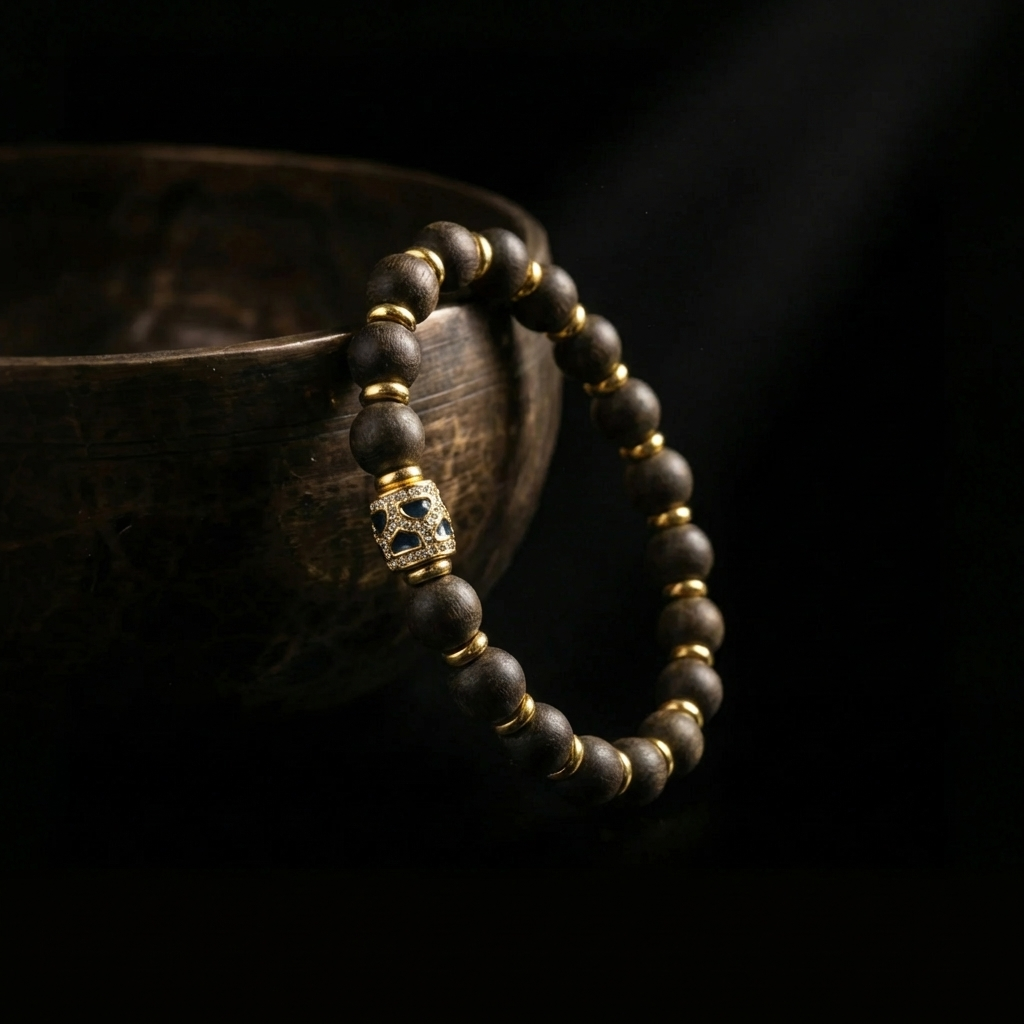 Agarwood focus bracelet resting against a dark rustic bowl, showcasing the contrast between the natural earthy wood and the crafted enamel centerpiece.