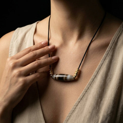 Woman wearing the Earth Horizon Banded Agate grounding necklace, showcasing the beautiful 50mm focal stone resting gracefully across her chest over a neutral linen dress.