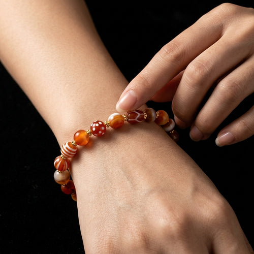 A person tracing the smooth, fire-baked patterns of the Etched Agate calming bracelet on their wrist, using it as a cooling worry stone to halt emotional burnout.