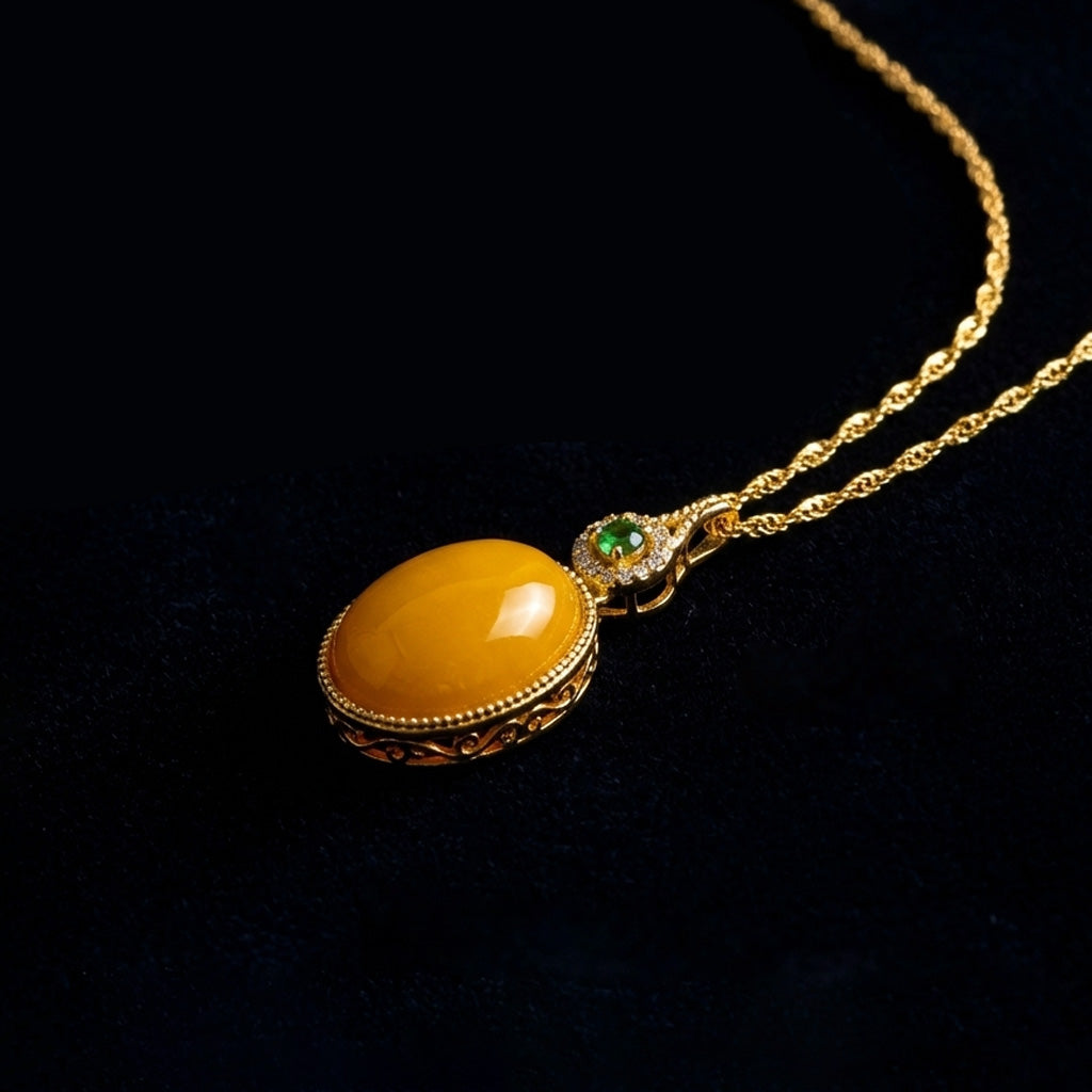 Close-up of the Golden Seed oval amber focus necklace with a subtle green accent, resting on a dark background.