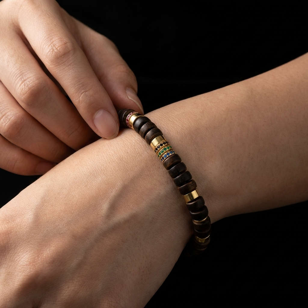 A person touching the multi-color pavé crystal ring on their disc-cut Sandalwood bracelet, using the tactile metallic node as a physical override to uncover clarity.