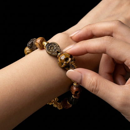 Person tracing the hand-carved skull beads of their grounding bracelet, using the complex tactile texture as a physical reality check for daily anxiety.