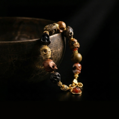 Memento Mori skull bracelet resting against a dark rustic bowl, highlighting the intricate carvings and heavy dangling agate charm.