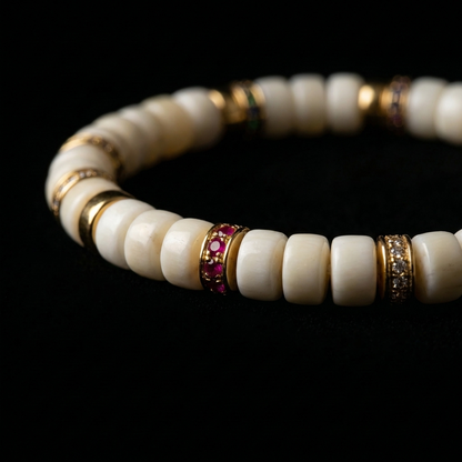 Close-up of the Silent Jewels shed antler grounding bracelet on a dark background, showing the smooth bone-white discs and colorful pavé rings.