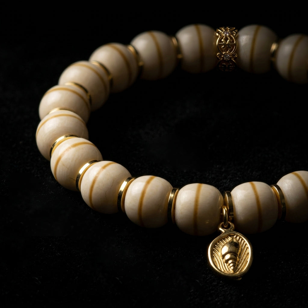 Macro view of the Bodhi seed grounding bracelet on a black background, emphasizing the vertical striations on the 11mm pale seeds and the gold shell charm.