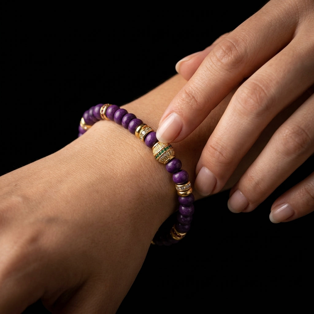 Woman wearing the Vivid Pulse Sugilite grounding bracelet on her wrist, showcasing the striking deep purple stones and ornate gold accents against her skin.