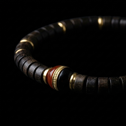 Close-up of the Sandalwood and Agate focus bracelet, featuring 7mm dark precision disc-cut wooden beads, 18K gold spacers, and a dual-tonal red and black agate focal node.