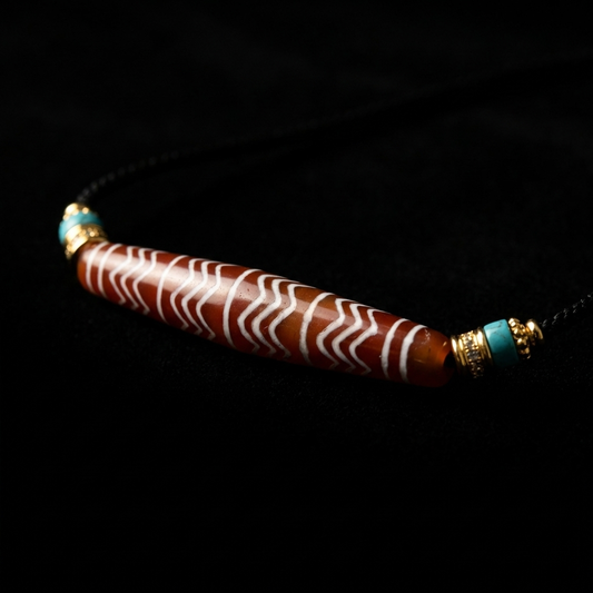 Close-up of the massive 70mm Agate grounding necklace, featuring a reddish-brown cylindrical stone with white wave motifs, turquoise nodes, and pavé-accented 18K gold spacers.